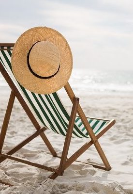 Straw hat kept on empty beach chair at tropical sand beach